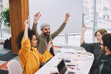 Fototapete - Young diversity group of creative students celebrating successful project and good results of collaboration in stylish office.Accomplished male and female designers have won working in team dream