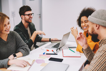 Fototapete - Positive male and female designers discussing creative ideas for developing startup project teamworking in office.Diversity group of cheerful hipsters students laughing during collaboration at desktop