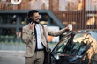 © Zamrznuti tonovi - Businessman talking on phone holding coffee outside car