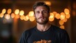 © svastix - A young bearded man wearing a black shirt stands against a background with warm bokeh lights, giving a cozy and inviting atmosphere to the portrait image.