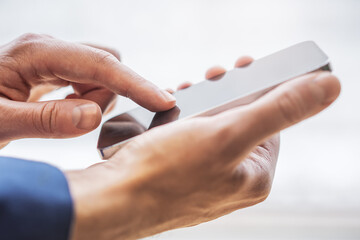 Poster - Close detail of a man operating his latest-model smartphone surrounded by the unfocused hustle of his office