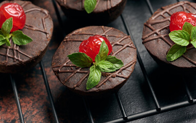 Wall Mural - Deliciously rich chocolate brownies garnished with vibrant cherries and mint leaves, resting on a black wire rack