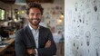 © frank29052515 - Confident businessman in a creative workspace smiling with arms crossed in front of a wall filled with light bulb sketches representing ideas and innovation
