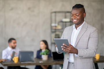 Leinwandbilder - A diverse team works together in a sleek office, with one member engaging on a tablet while others discuss ideas and strategies. The atmosphere is vibrant and focused on success.