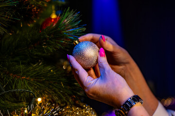 Wall Mural - Woman's hands decorate the Christmas tree with a silver ball.