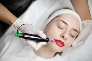 A young woman relaxes as a skilled makeup artist applies a long-lasting lip color treatment. This pampering beauty procedure takes place in a comfortable salon setting.