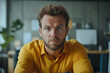 © Bohdan - Man with blue eyes wears yellow shirt in modern office