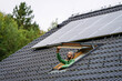 © Halfpoint - Mature man closing skylight, roof window, solar panels above him. Sustainable lifestyle and green household.