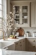 © kucret - Rustic, modern kitchen with light beige cabinets, marble countertop, white sink, and spring blossoms.