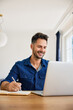 © baranq - Adult man studying online at home using laptop taking notes in notebook