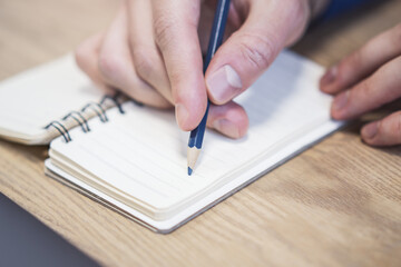 Poster - Close perspective of a man's hand making entries in a notepad, with a soft blur in the surrounding