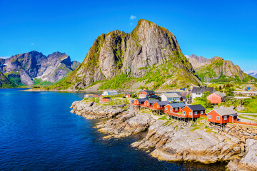 Wall Mural - a picturesque scene of red cabins perched on the rocky coastline of norway, surrounded by dramatic m