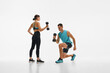 © master1305 - Muscular young man and fit young woman, couple in sportswear training together with dumbbells against white studio background. Concept of sport, active and healthy lifestyle, workout, fitness