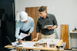 © Nuttapong punna - Professional collaboration in architecture. Two engineers work on construction plans, using tools like laptops, tablets, and scale models.