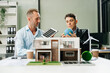 © Nuttapong punna - businesspeople standing neare table looking at model of building from residential project. Green business company and Solar Energy Environment city