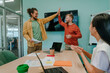 © Westend61 - Happy businessmen giving high-five to each other near businesswoman sitting in office