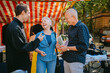 © Westend61 - People conversing and smiling at a flea market outdoors.