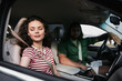 © SHOTPRIME STUDIO - A young couple enjoying a car ride in a modern vehicle, with the woman looking playfully out the window and the man focused on driving