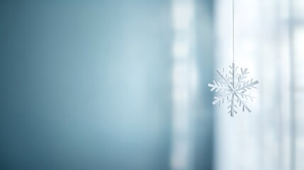 Poster - A delicate paper snowflake dangles gently against a frosted glass window, creating a serene winter atmosphere, with an inviting soft blue backdrop