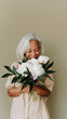 © bosotochka - An elderly woman holds a beautifully bouquet with peonies. Pastel palette. Happy Mother's Day or Happy Women's day, birthday. Space for text