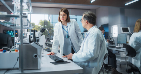 Poster - Female Research Scientist Having a Conversation with a Bioengineer About the Effects of Different Pharmaceutical Drugs. Employees Looking at an Online Report in a Modern Science Laboratory