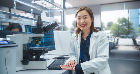 Aufkleber - Genetic Research Scientist Working on a Desktop Computer in an Applied Science Laboratory. Portrait of a Beautiful Asian Lab Engineer in White Coat Looking at Camera and Smiling