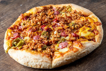 Wall Mural - Close-up of a delicious pizza topped with crispy bacon, pepperoni, green peppers, and melted cheese, served on a rustic wooden surface. Perfect for food lovers and culinary themes.