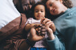 © BullRun - Blurred photo of diverse family with selective focus on hands intertwined, child centered between parents capturing essence of unity and unconditional love and genuine emotional connection