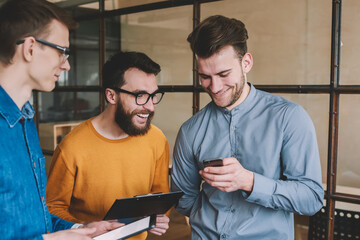 Poster - Happy male friends reading positive sms message via app for chatting on mobile phone, young smiling man using wireless 4g internet on smartphone device for watching funny videos with colleagues