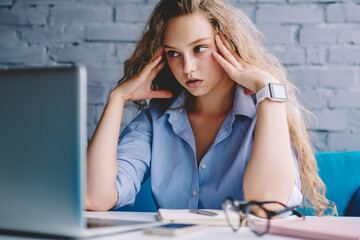 Fototapete - Frustrated female freelancer feeling tired of deadline watching videos on laptop device during remote work in coworking space, unhappy hipster girl have trouble with bank payment via netbook