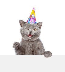 Poster - Winkung cat wearing party's cap looks above blank white banner. isolated on white background