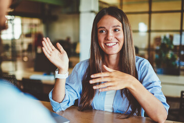 Fototapete - Happy successful hipster girl explaining information to male friend sitting in front, positive man and woman talking and discussing ideas for new startup project at spending time in coworking space