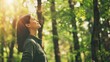 © Svyatoslav Lypynskyy - A relaxed woman stands in a lush green forest taking a deep breath of fresh air. Sunlight filters through the trees illuminating her calm expression as she connects with nature.