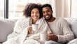 © Soloviova Liudmyla - Cozy living room scene with joyful middle-aged african american couple on sofa, wrapped in soft knitted blanket. They hold warm coffee cups and smiling. Natural light creates warm inviting ambiance.