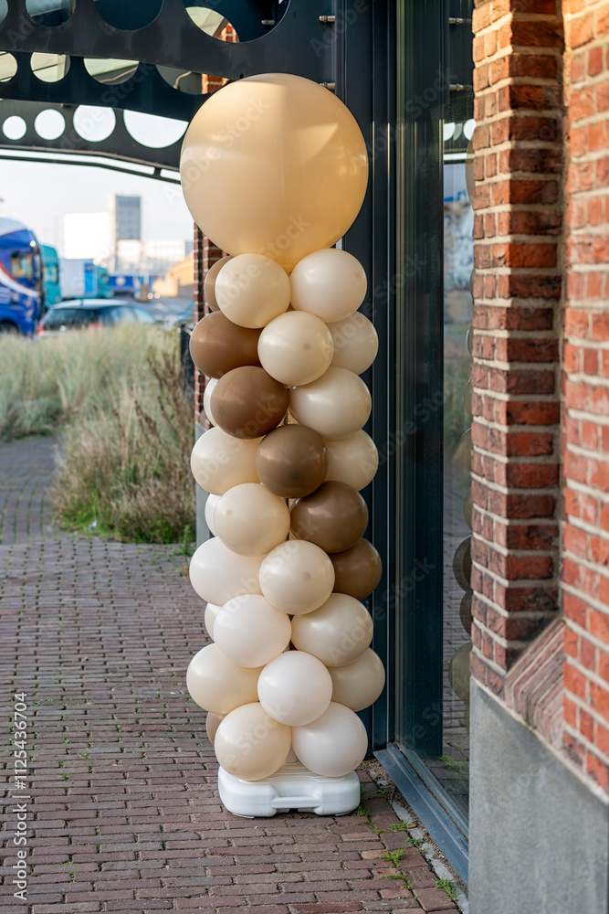 balloons in various shades of brown hang outside as decoration on a pole next to a shop