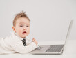 © Михаил Решетников - A cute child wearing a suit holds glasses and lies behind a laptop.