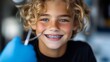 © VISUAL BACKGROUND - A young boy with braces smiles while holding a toothbrush