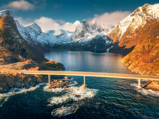 Wall Mural - aerial view of djupfjord bridge crossing the fjord with snowy mountains, colorful sky in golden hour