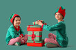 © Pixel-Shot - Cute little boys in elf costumes with Christmas presents on green background