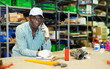© JackF - African-american man storehouse worker standing at workbench and having telephone conversation.