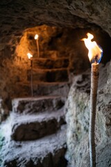 Poster - A torch provides light in the darkness of a cave