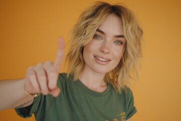 Poster - A woman wearing a green shirt points at the camera with her hand