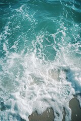 Poster - A wave crashes onto a sandy beach with calm and clear water