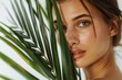 © Ева Поликарпова - A close-up of a woman's face with freckles, holding a palm leaf