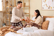 © Pixel-Shot - Happy young couple with cups of tea in bedroom at home on autumn day