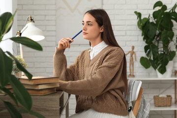 Canvas Print - Beautiful thoughtful female student with stacks of books studying at table in room