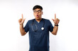© ArvStd - Amazed and impressed asian male doctor, physician or nurse in scrubs looking wondered, pointing up, white background