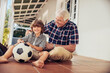 © Marko Geber - Grandfather playing soccer with grandson on home porch