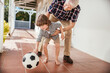 © Marko Geber - Grandfather playing soccer with grandson on home porch
