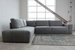 © otterspeer.com Stock - Gray sectional sofa with a patterned rug on a concrete floor.  Industrial style.